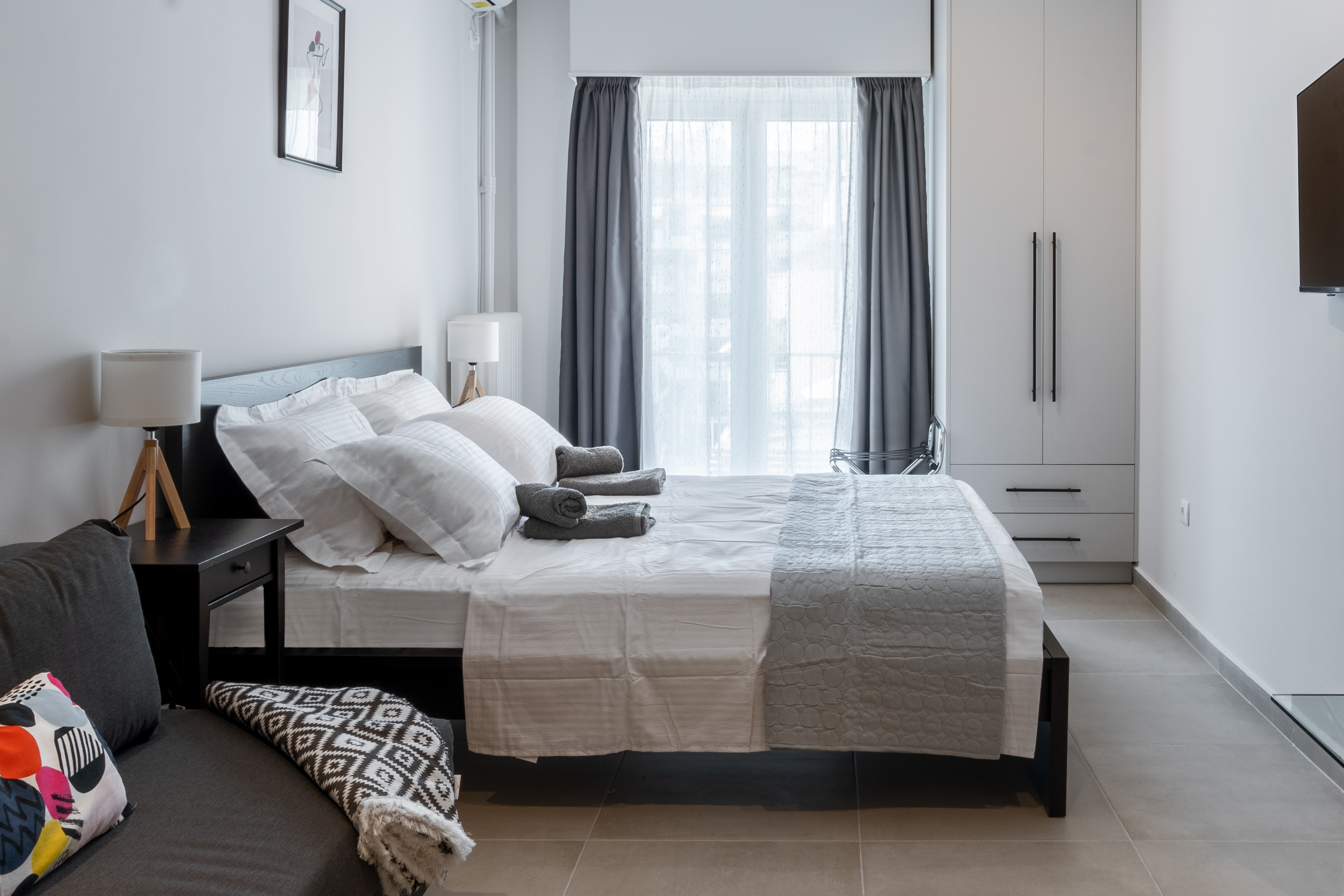 Comfortable queen bed next to balcony with natural light